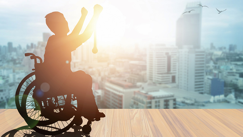 A black silouhette of a person in a wheelchair over a city skyline