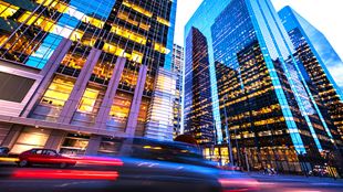 Car speeding past tall skyscrapers in a financial district