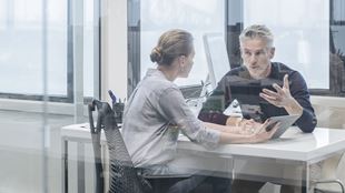 man and woman in discussion at desk