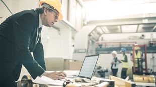 homme d'affaires avec un chapeau de construction en regardant ordinateur portable