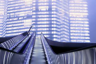 Upwards shot of empty escalator in front of tall modern buildings