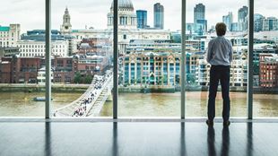 person looking out of window looking at city