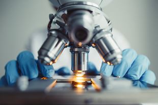 Close-up of a person using a microscope wearing gloves