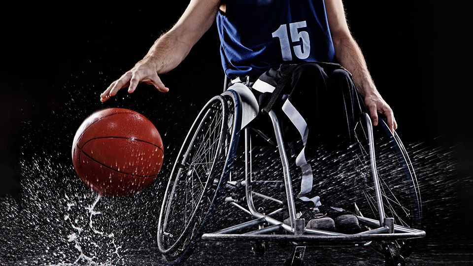 Joeur de basketball paraplégique sur fond noir.