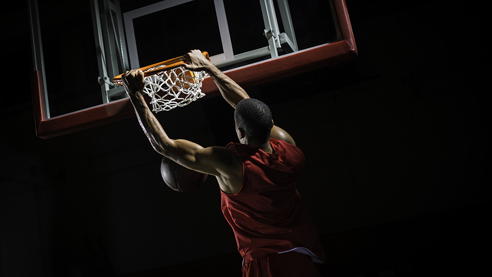 Un joueur de basketball se tiens au panier.